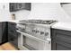 Close-up view of the stainless steel gas range with ample counter space and custom cabinetry at 10862 Serenbe Ln, Chattahoochee Hills, GA 30268