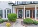 A closer view of the front door, framed by brick, black shutters and manicured bushes at 3906 Elm Trace Ct, Loganville, GA 30052
