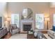 Cozy living room with fireplace, large round mirror, hardwood floors, and bright windows at 3906 Elm Trace Ct, Loganville, GA 30052