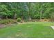 Expansive backyard featuring lush green lawn, mature trees, landscaping, and a charming storage shed at 4204 Woodfare Nw Ln, Kennesaw, GA 30152