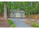 Backyard shed with neutral paint, double doors, and surrounding landscaping and trees at 4204 Woodfare Nw Ln, Kennesaw, GA 30152