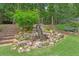 Backyard waterfall feature cascading down a rock formation surrounded by lush landscaping at 4204 Woodfare Nw Ln, Kennesaw, GA 30152