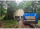 Rear exterior view with garage and a trailer, backed by a heavily wooded landscape at 33 Powder Dr, Dallas, GA 30157