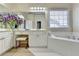 Elegant bathroom features a soaking tub, vanity, white cabinetry, and decorative wallpaper at 1635 Lake Heights Cir, Dacula, GA 30019