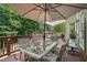 Enjoy outdoor dining on this wood deck with a glass table and chairs, shaded by an umbrella and lush greenery at 223 Sterling Brook Ln, Canton, GA 30114