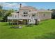 Expansive backyard view of home featuring a deck, lush lawn, and mature trees at 5661 Rutland Trce, Lithonia, GA 30058