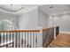 Hallway with staircase features wood flooring and iron railing beneath a chandelier at 5661 Rutland Trce, Lithonia, GA 30058
