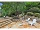 Lush backyard retreat with a serene waterfall feature, flagstone patio, and inviting outdoor seating amidst mature trees at 145 Ardsley Ln, Alpharetta, GA 30005