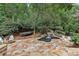 Picturesque backyard features a pool with a waterfall, a stone patio, and an inviting fire pit surrounded by mature trees at 145 Ardsley Ln, Alpharetta, GA 30005