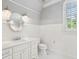 Elegant powder room with white wainscoting, a decorative mirror, and a window at 145 Ardsley Ln, Alpharetta, GA 30005