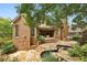 Back exterior of the brick home featuring a covered porch, a stone patio, and an in-ground pool surrounded by lush greenery at 145 Ardsley Ln, Alpharetta, GA 30005