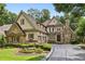 Elegant front exterior features stone and wood accents with a well manicured lawn and landscaping at 145 Ardsley Ln, Alpharetta, GA 30005