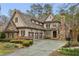 Beautiful stone and wood exterior with an attached three-car garage and manicured landscaping at 145 Ardsley Ln, Alpharetta, GA 30005