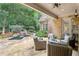 Covered patio with comfortable wicker seating overlooking a beautifully landscaped backyard featuring a pool and lush greenery at 145 Ardsley Ln, Alpharetta, GA 30005