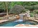 Backyard pool with waterfall feature surrounded by mature trees at 145 Ardsley Ln, Alpharetta, GA 30005