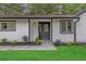 Inviting home entrance with a black front door, white siding, well-kept lawn, and manicured landscaping at 373 Hemlock Dr, Lawrenceville, GA 30046