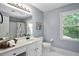 Well-lit bathroom featuring white cabinetry, a large mirror, and a window overlooking the lush greenery outside at 2316 Fripp Overlook Nw, Acworth, GA 30101