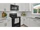 Close-up shot of the kitchen featuring white cabinets, black appliances, and granite countertops at 2316 Fripp Overlook Nw, Acworth, GA 30101