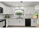 Well-lit kitchen featuring black appliances, white cabinets, marble countertops, and view of backyard patio at 2316 Fripp Overlook Nw, Acworth, GA 30101