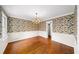 Dining room featuring hardwood floors, crown molding, floral wallpaper and an elegant chandelier at 2179 Mountclaire Ct, Stone Mountain, GA 30087