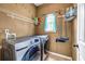 Functional laundry room featuring stainless steel washer and dryer, storage shelving and a window at 5485 Shirewick Ln, Lithonia, GA 30058