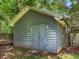 Weathered gray shed in a backyard featuring a double door and adjacent fence at 4720 Hull Rd, Conyers, GA 30094