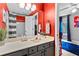 Red bathroom showcasing a large mirror, gray vanity, bright-colored wall, and a shower with a striped curtain at 3229 Dunlin Lake Rd, Lawrenceville, GA 30044