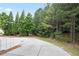 View of an exterior concrete driveway and a tree-filled green backyard space with a picnic table at 4130 Stonecypher Rd, Suwanee, GA 30024
