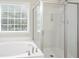 Modern bathroom featuring a separate soaking tub and glass-enclosed shower under a window at 4130 Stonecypher Rd, Suwanee, GA 30024