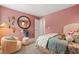 Stylish bedroom featuring a bed, chair, round mirror, and pink walls at 229 Paisley Way, Locust Grove, GA 30248