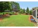 A sprawling backyard featuring lush green grass, mature trees, and a swing set at 335 Scarborough Way, Alpharetta, GA 30022