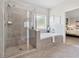 Bright bathroom with glass-enclosed shower, soaking tub, and neutral tile at 4090 Sierra Knolls Ct, Cumming, GA 30040