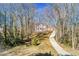 View of a two-story home on a hillside with a long driveway, surrounded by mature trees at 5050 Brownwood Dr, Powder Springs, GA 30127
