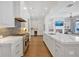 A white kitchen features stainless appliances, a large island, and herringbone backsplash, with the Gathering room in view at 102 Grand Cres, Alpharetta, GA 30009