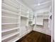 Bright walk-in closet featuring white shelving units with dark wood flooring at 102 Grand Cres, Alpharetta, GA 30009