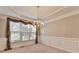 Elegant dining room boasts tray ceiling, wainscoting, chandelier, and large window at 1301 Dayspring Trce, Lawrenceville, GA 30045