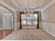 Open dining room features wainscoting, tray ceiling, chandelier, and view into front yard at 1301 Dayspring Trce, Lawrenceville, GA 30045