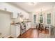 Modern kitchen boasts white cabinetry, stainless steel appliances, granite counters, and a charming breakfast area at 215 Nina Circle Cir, Locust Grove, GA 30248