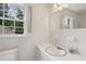 Classic bathroom featuring white tile, large mirror, window for natural light and white fixtures at 3755 Kayanne Ct, Tucker, GA 30084
