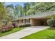 Charming brick home featuring a covered driveway and lush landscaping with flowering trees and shrubs at 3755 Kayanne Ct, Tucker, GA 30084