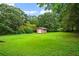 Expansive backyard featuring lush green grass, mature trees, and a storage shed at 140 Carriage Cir, Stockbridge, GA 30281