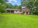Back exterior of the home with a covered porch, brick facade, and expansive grassy yard at 140 Carriage Cir, Stockbridge, GA 30281