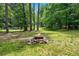 Backyard with a fire pit surrounded by a green lawn and woods at 3620 Beaver Cove Rd, Cumming, GA 30041