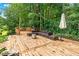 Wooden deck with outdoor sectional, grill and an umbrella surrounded by lush landscaping at 3620 Beaver Cove Rd, Cumming, GA 30041