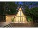 A-frame home featuring a wooden deck with seating and large glass windows surrounded by a lush, green landscape at twilight at 3620 Beaver Cove Rd, Cumming, GA 30041