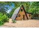 A-frame home showcasing wood siding, a metal roof, round windows, and ample parking space at 3620 Beaver Cove Rd, Cumming, GA 30041