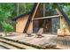A-frame home featuring a wooden deck with seating and large glass windows surrounded by a lush, green landscape at 3620 Beaver Cove Rd, Cumming, GA 30041