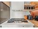 A close-up of the kitchen with a stovetop on a white countertop and stainless steel appliances at 3620 Beaver Cove Rd, Cumming, GA 30041