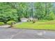 Ranch-style home with a well-manicured lawn and driveway leading to an attached garage, surrounded by mature trees at 5577 Whittondale Rd, Lithonia, GA 30058
