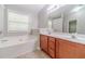 Bathroom boasts soaking tub, large mirror, double sink vanity, and neutral tile at 1346 Upshur Pl, Buford, GA 30519